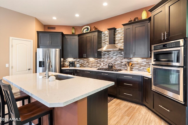 kitchen featuring a breakfast bar, a kitchen island with sink, sink, and stainless steel appliances