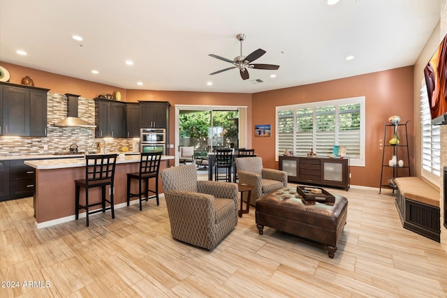 living room featuring light hardwood / wood-style flooring, ceiling fan, and a healthy amount of sunlight