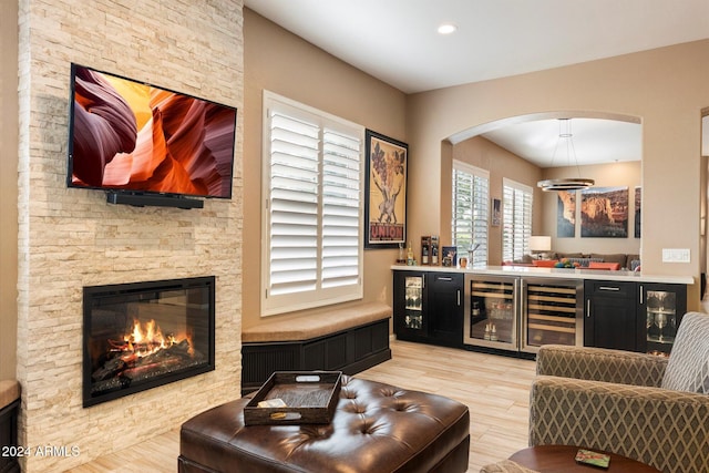 bar with light hardwood / wood-style floors, a fireplace, and wine cooler