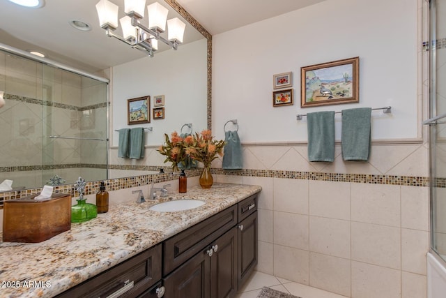 bathroom with vanity, a notable chandelier, tile walls, and walk in shower