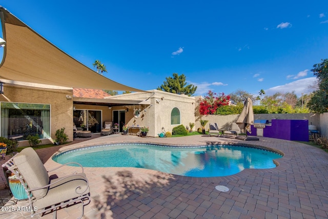 view of pool with exterior kitchen and a patio area