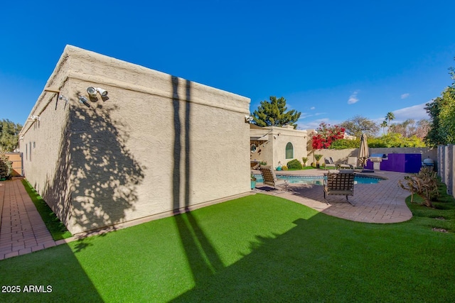 back of property with a fenced in pool, a lawn, and a patio area