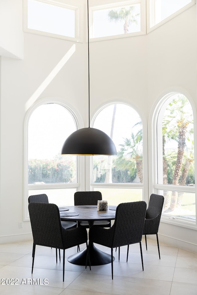 tiled dining space featuring plenty of natural light and a towering ceiling