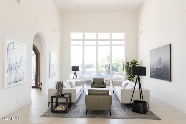 living room featuring light tile patterned floors and a towering ceiling