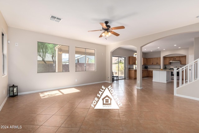 tiled spare room with ceiling fan with notable chandelier