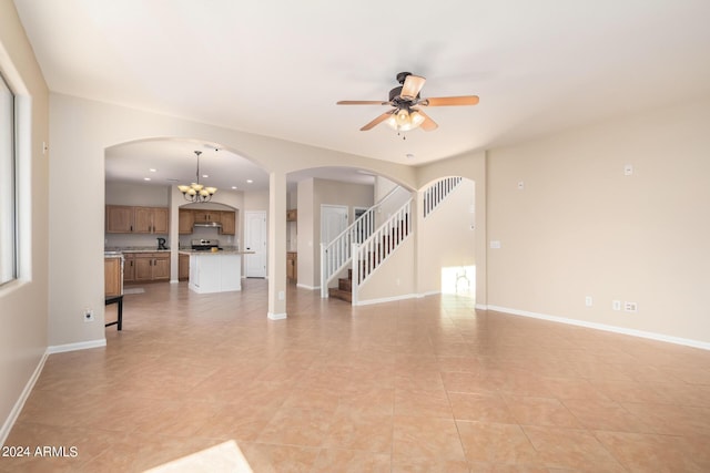 unfurnished living room featuring ceiling fan with notable chandelier and light tile patterned floors