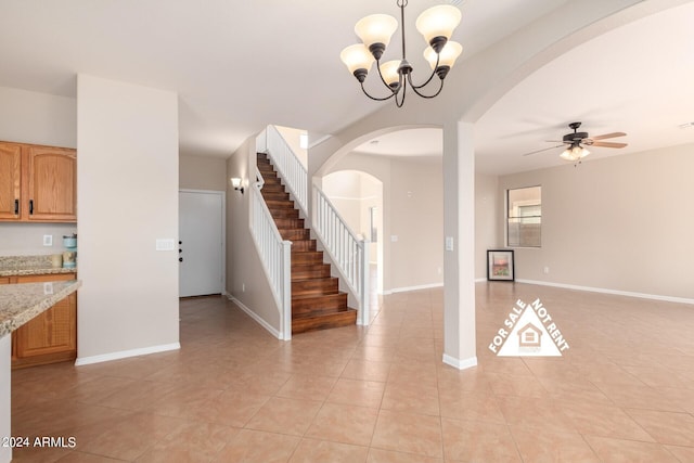 unfurnished living room with light tile patterned flooring and ceiling fan with notable chandelier