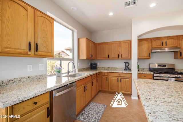 kitchen with light stone counters, sink, light tile patterned floors, and stainless steel appliances