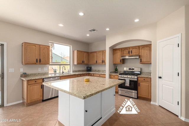 kitchen with light stone countertops, a center island, sink, stainless steel appliances, and light tile patterned flooring