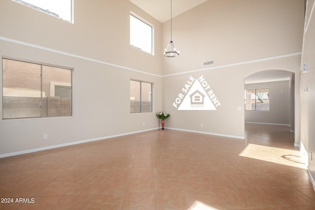 unfurnished living room featuring tile patterned flooring, a towering ceiling, and a chandelier