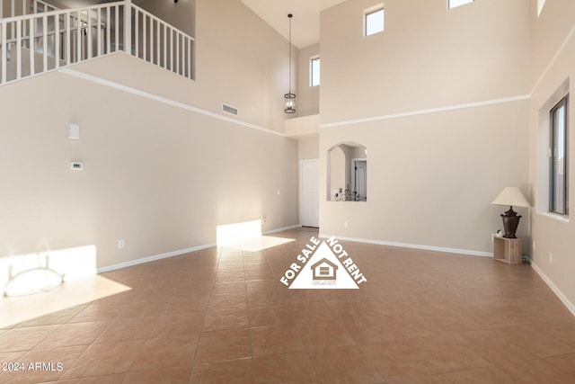 unfurnished living room featuring tile patterned floors and a high ceiling