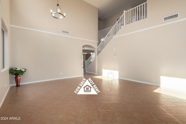 unfurnished living room featuring tile patterned flooring, a high ceiling, and a notable chandelier