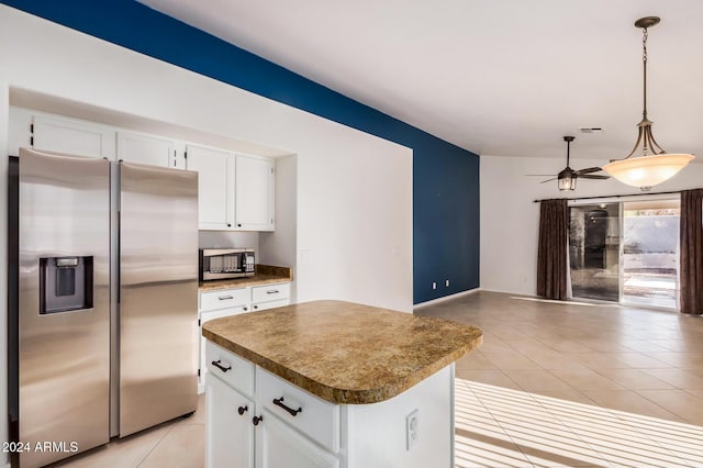 kitchen with stainless steel appliances, light tile patterned floors, decorative light fixtures, a center island, and white cabinetry