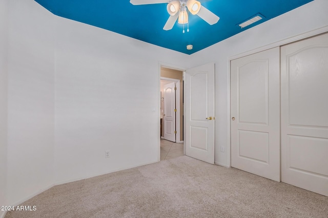 unfurnished bedroom featuring ceiling fan, light carpet, and a closet