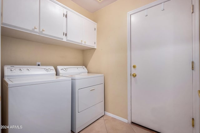 clothes washing area with washer and dryer, light tile patterned floors, and cabinets