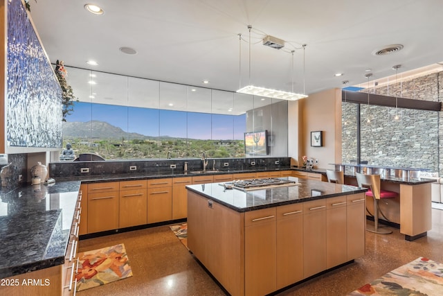 39602 N Charles Blair Macdonald Rd, Scottsdale, AZ 85262 - kitchen with stainless steel gas cooktop, backsplash, dark stone counters, a center island, and decorative light fixtures