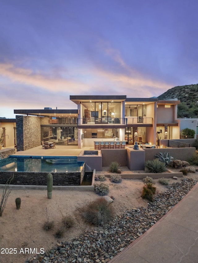 39602 N Charles Blair Macdonald Rd, Scottsdale, AZ 85262 - view of front of home with a balcony, an infinity pool, a patio, stucco siding, and exterior kitchen
