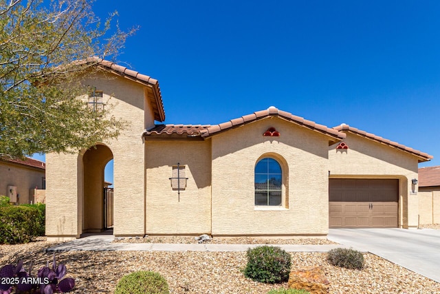 mediterranean / spanish-style house featuring stucco siding, an attached garage, concrete driveway, and a tiled roof