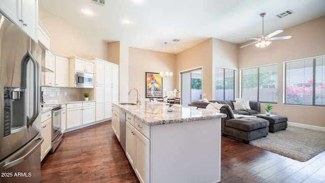 kitchen featuring sink, stainless steel appliances, backsplash, a kitchen island with sink, and white cabinets