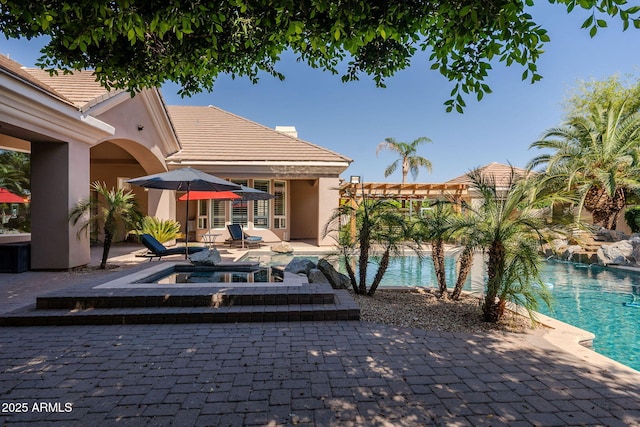 exterior space featuring an in ground hot tub, a patio, stucco siding, and an outdoor pool