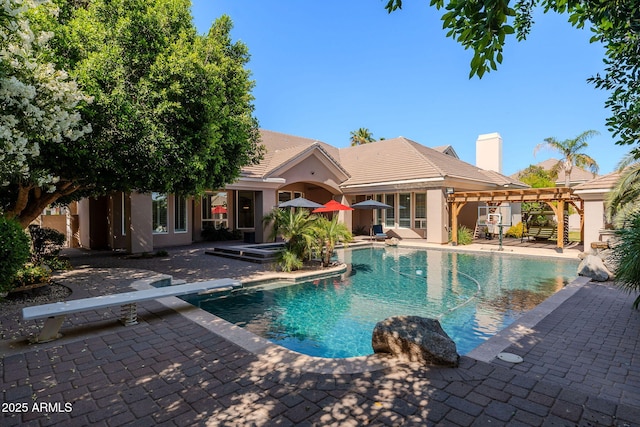 outdoor pool with a patio area, a diving board, and a jacuzzi