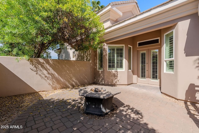 view of patio / terrace featuring a fire pit, fence, and french doors