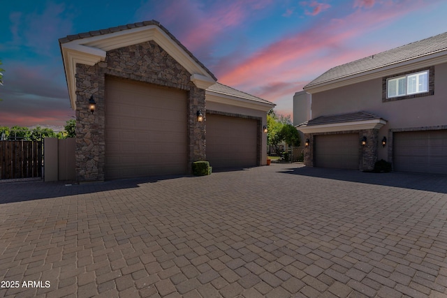 view of front of home with fence, stucco siding, stone siding, and driveway