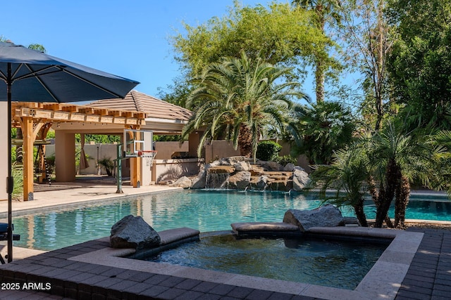 view of pool with a pool with connected hot tub, a pergola, a patio, and exterior kitchen