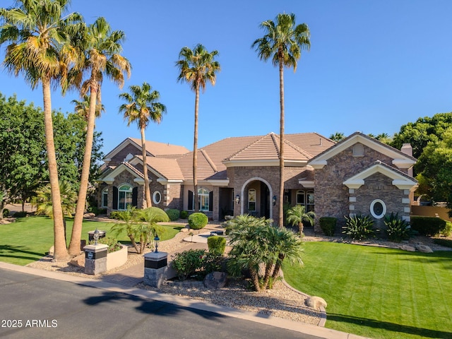 view of front of home with a tiled roof, stone siding, and a front yard