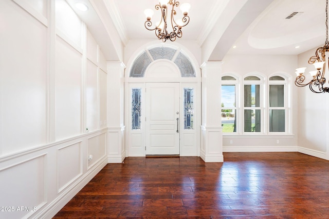 entryway featuring an inviting chandelier, decorative columns, visible vents, and dark wood finished floors