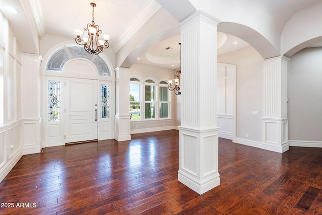 foyer entrance with arched walkways, ornate columns, and a notable chandelier