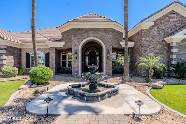 doorway to property with a tile roof and brick siding