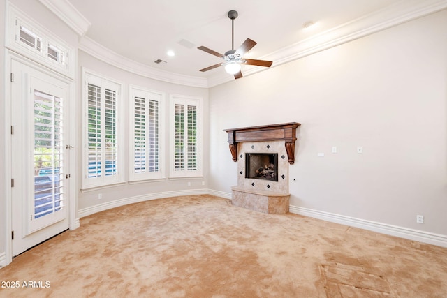 unfurnished living room with a fireplace with raised hearth, carpet, baseboards, ornamental molding, and ceiling fan