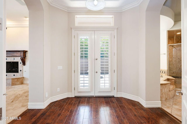 doorway with ornamental molding, baseboards, arched walkways, and dark wood-style floors