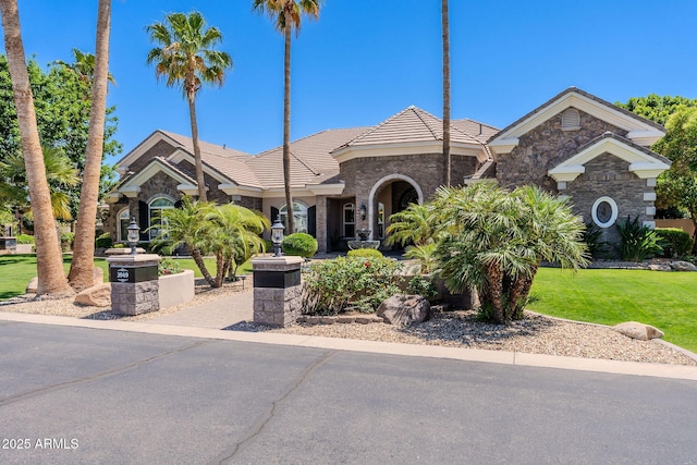 ranch-style house with stone siding, a tiled roof, and a front yard