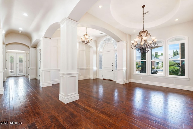 foyer featuring an inviting chandelier, visible vents, a decorative wall, dark wood-style flooring, and arched walkways