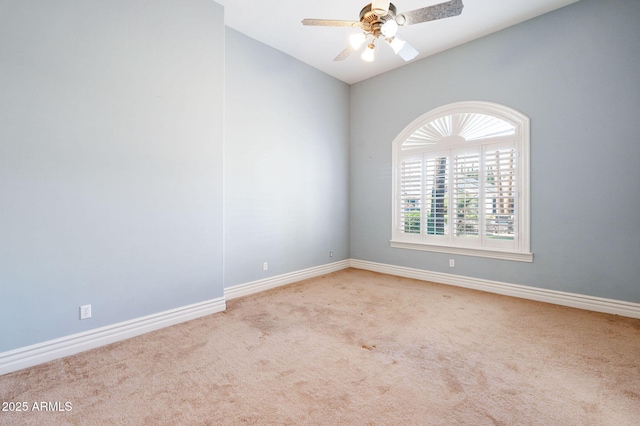 carpeted spare room featuring lofted ceiling, baseboards, and a ceiling fan