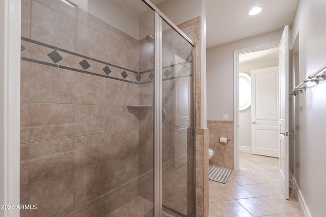 bathroom with toilet, a stall shower, tile patterned floors, tile walls, and recessed lighting