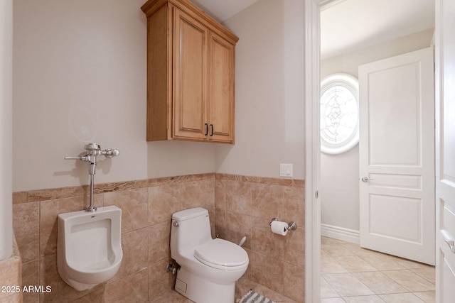 bathroom featuring wainscoting, tile patterned flooring, tile walls, and toilet