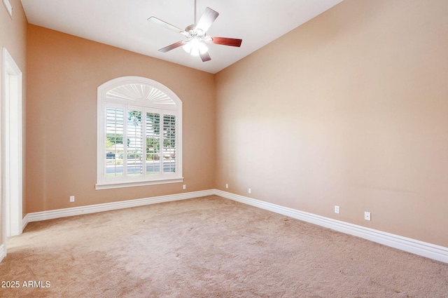 spare room with vaulted ceiling, carpet flooring, baseboards, and a ceiling fan