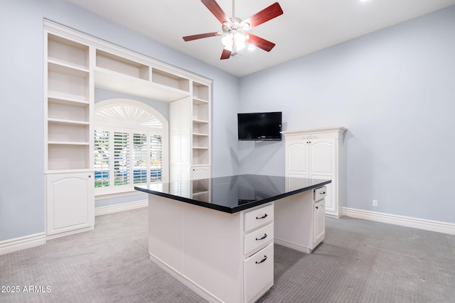 unfurnished office with a ceiling fan, baseboards, and light colored carpet