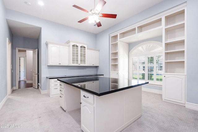 kitchen with light carpet, open shelves, baseboards, and dark countertops
