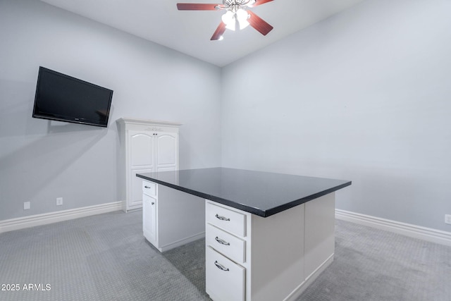 unfurnished office with a ceiling fan, light carpet, and baseboards