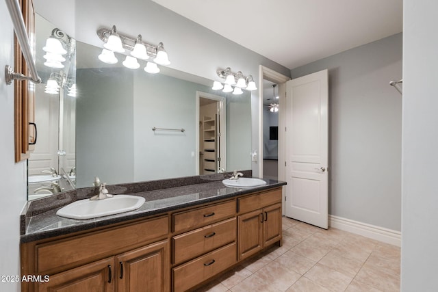 bathroom with double vanity, tile patterned floors, baseboards, and a sink