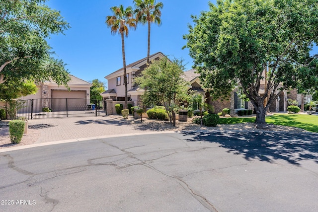 view of property hidden behind natural elements with a gate, fence, an attached garage, stucco siding, and decorative driveway