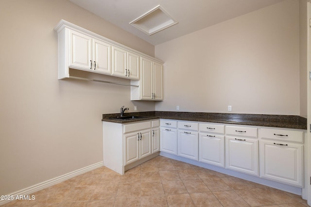 kitchen with white cabinetry, baseboards, light tile patterned floors, and a sink