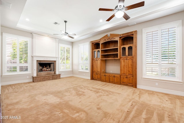 unfurnished living room featuring ceiling fan, a raised ceiling, baseboards, and visible vents