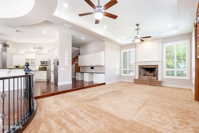 unfurnished living room featuring a raised ceiling, a ceiling fan, and recessed lighting
