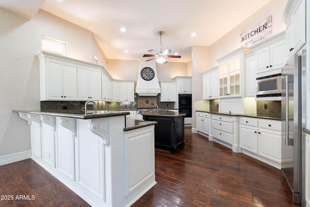 kitchen featuring a peninsula, ceiling fan, decorative backsplash, dark countertops, and appliances with stainless steel finishes
