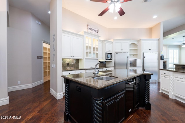 kitchen with built in appliances, a ceiling fan, a sink, a center island with sink, and dark wood-style floors
